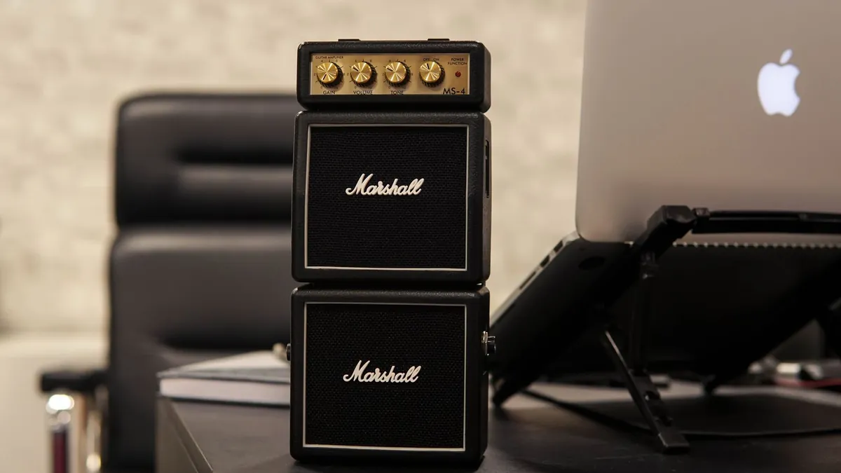 mini amplificador Marshall empilhado ao lado de um notebook em uma mesa de escritório