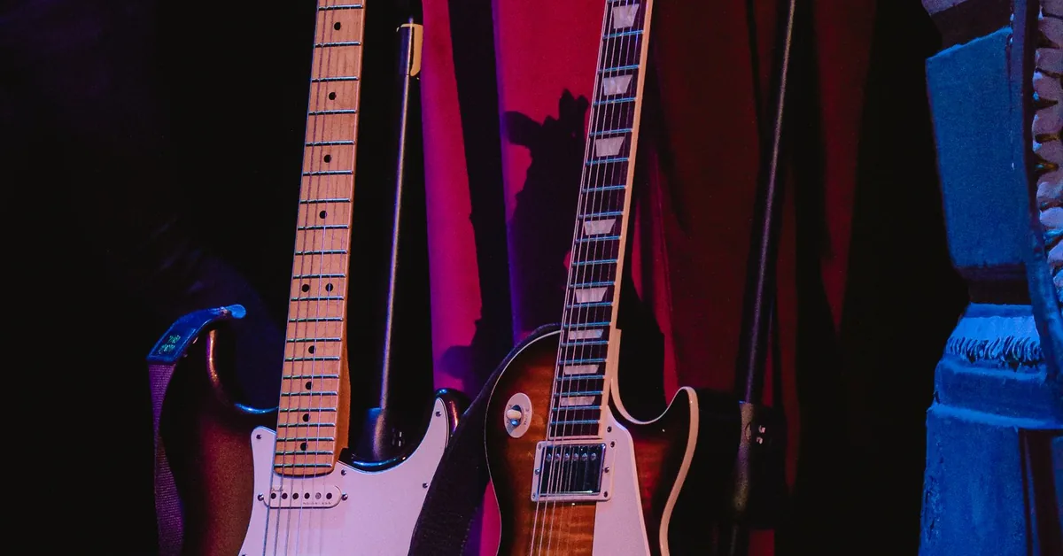 guitarras elétricas penduradas em um palco com iluminação rosa e azul