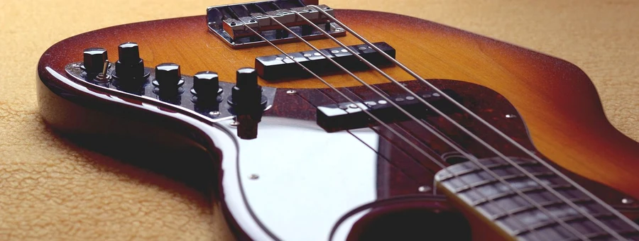 close-up dos knobs de controle e captadores de um baixo elétrico sunburst