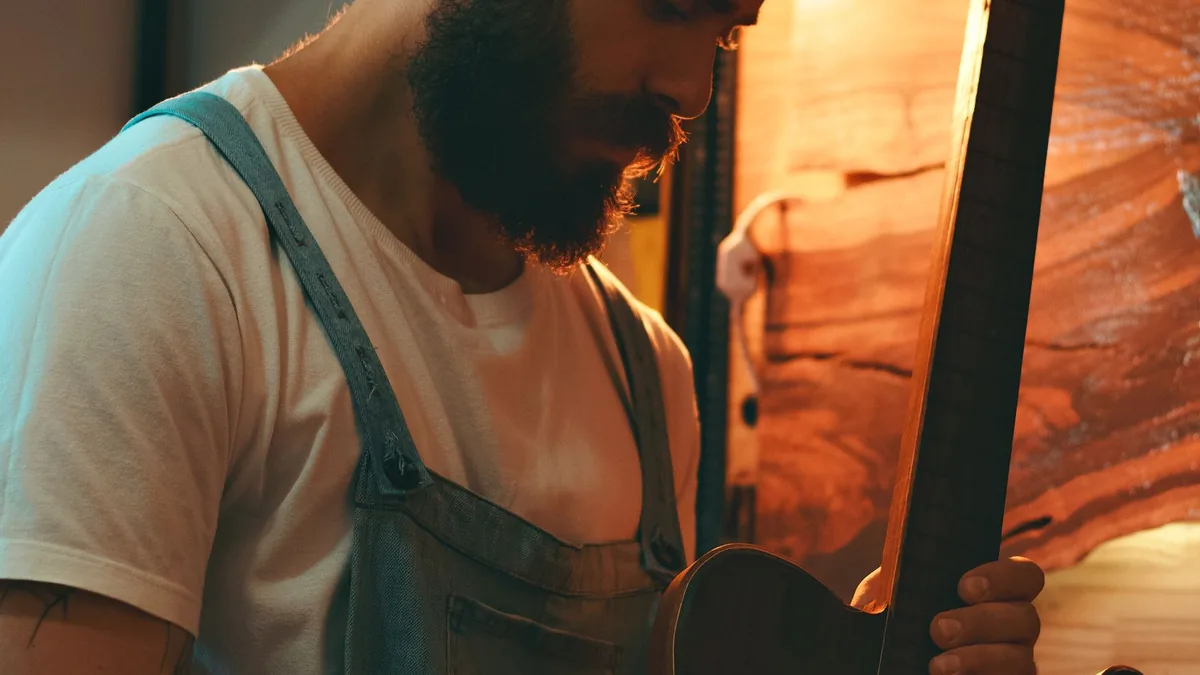 pessoa mirando ao longo do braço da guitarra para conferir a curvatura