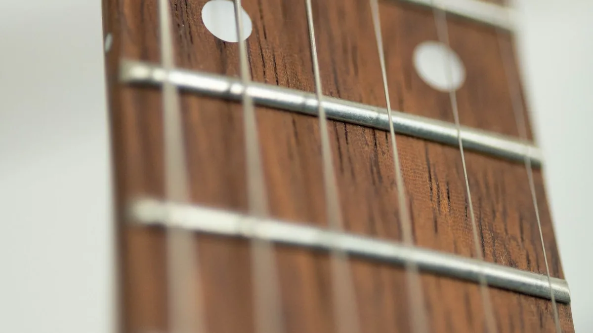 braço de guitarra elétrica visto de perto, escala escura com marcadores brancos e trastes