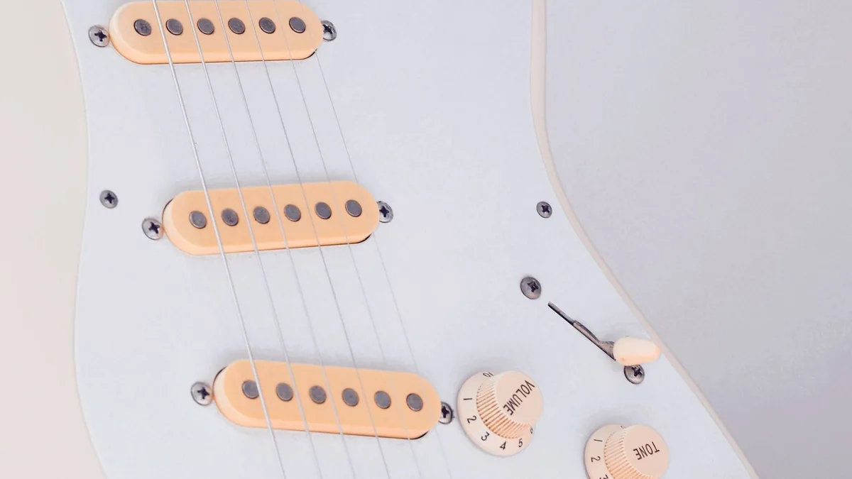 três captadores single coil vistos de cima no escudo branco, ao lado dos knobs de volume e tone