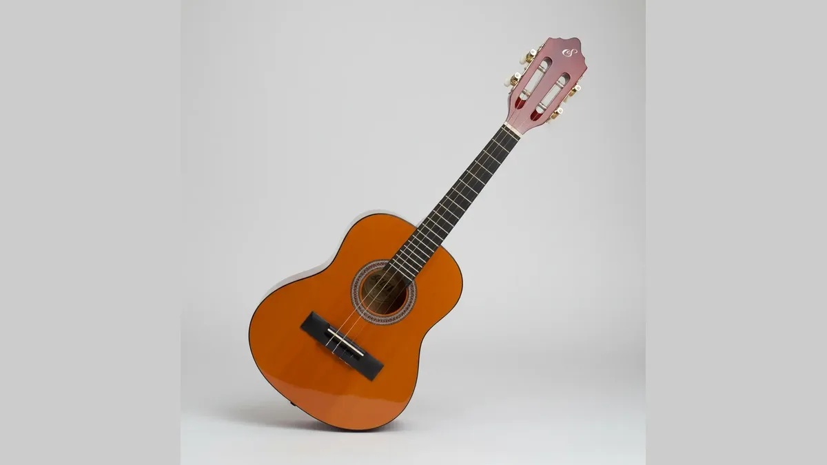 cavaquinho acústico inclinado contra um fundo cinza liso, com as quatro tarraxas à mostra