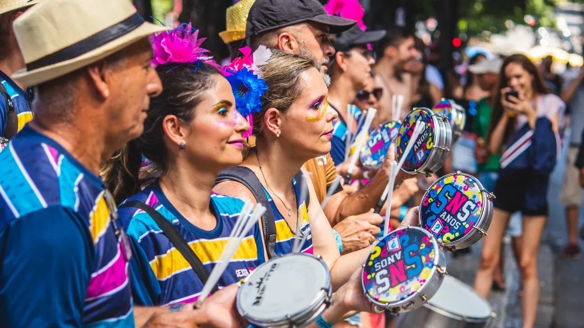 músicos de samba de camisa colorida tocando tamborim e instrumentos de percussão em uma roda na rua