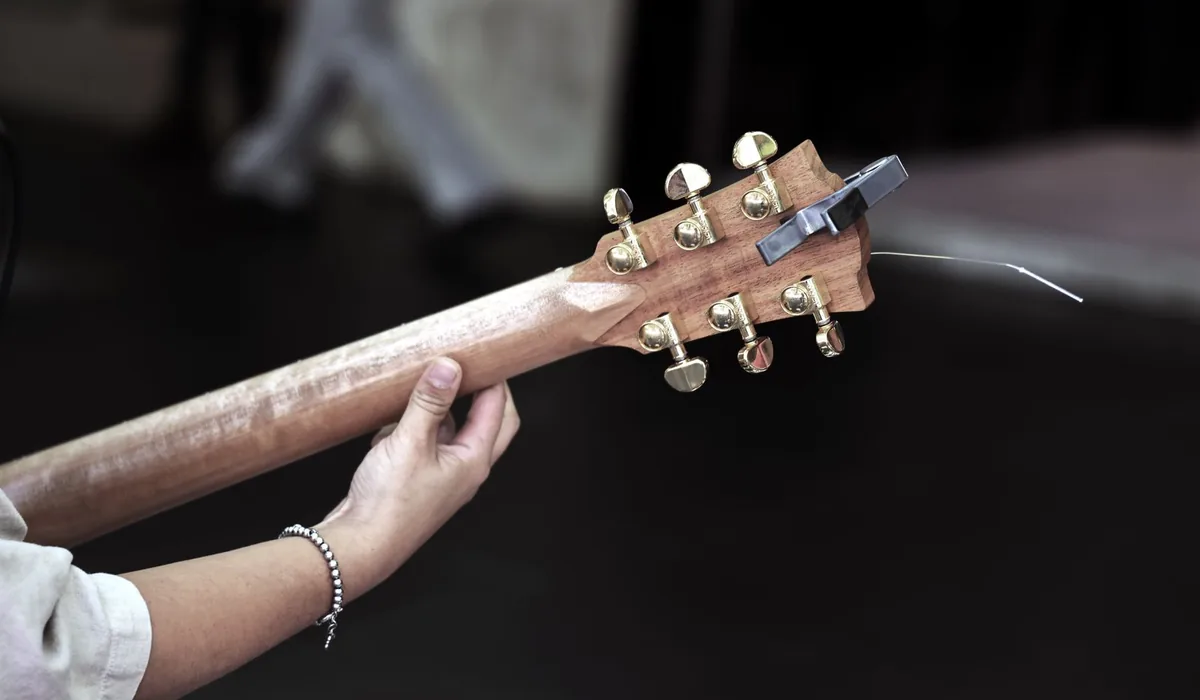 mão ajustando a tarraxa do violão durante a afinação