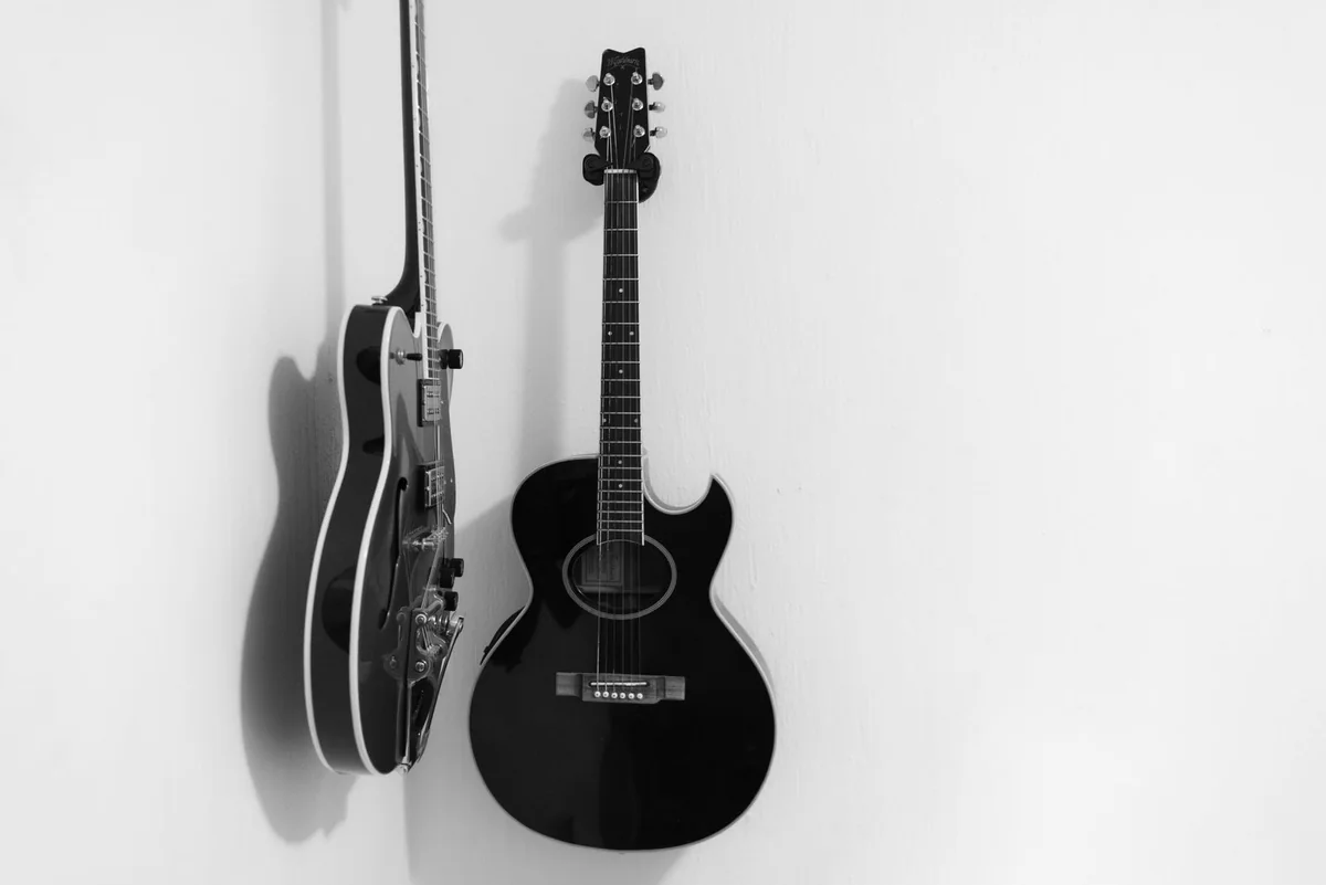 violão e guitarra elétrica pendurados lado a lado na parede branca