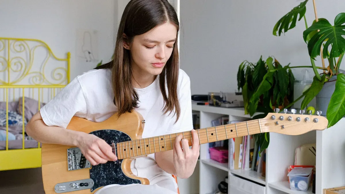 guitarrista iniciante tocando guitarra em casa em um quarto iluminado