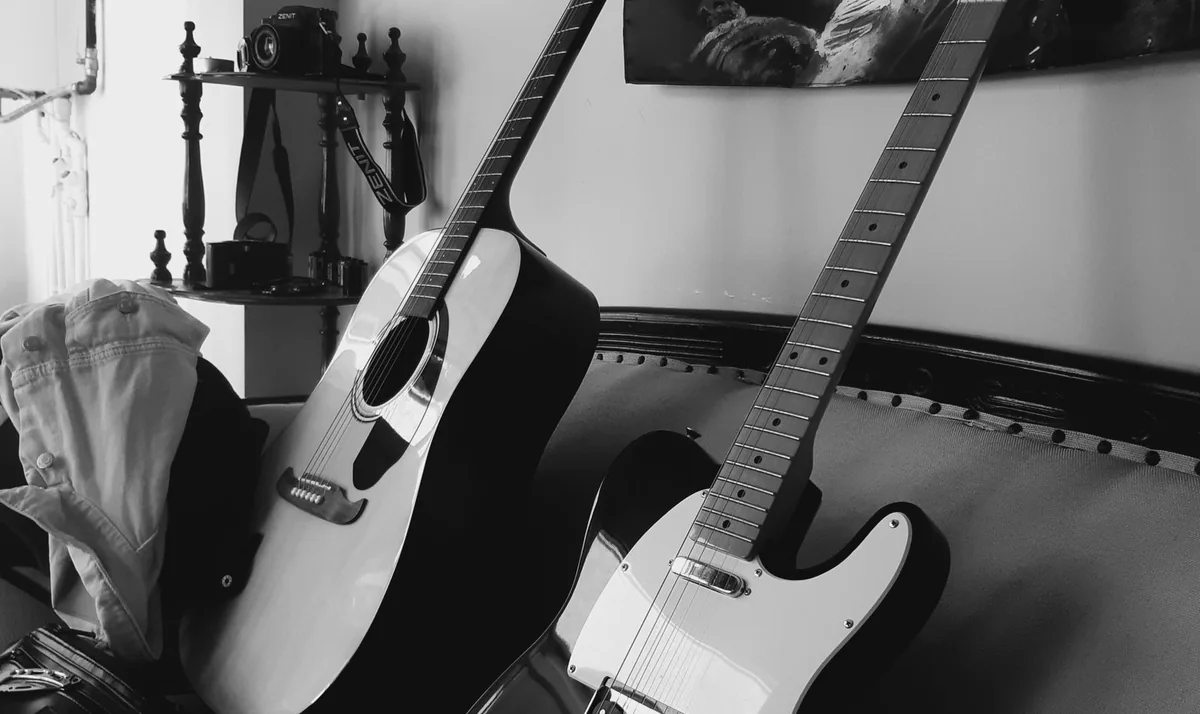 violão de aço e guitarra Telecaster encostados lado a lado, em foto preto e branco
