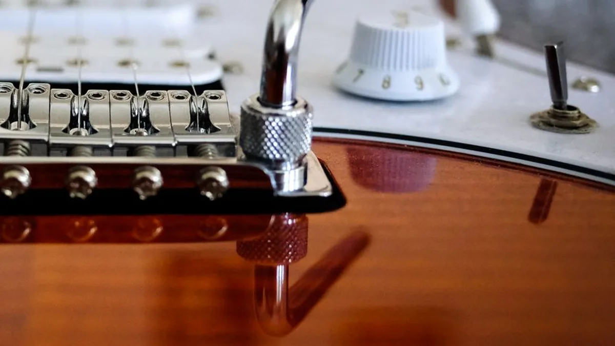 close do botão de volume e da chave seletora de uma guitarra Stratocaster com pickguard branco