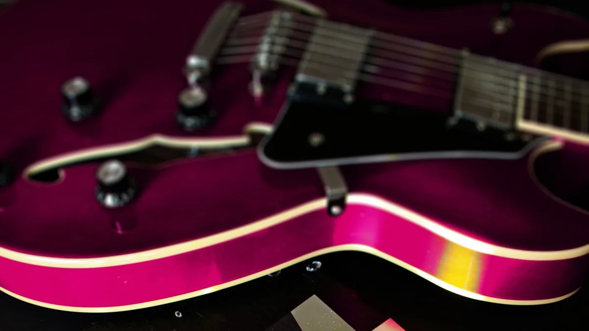 corpo de guitarra semi-acústica magenta metálico com filete branco e captadores pretos em close