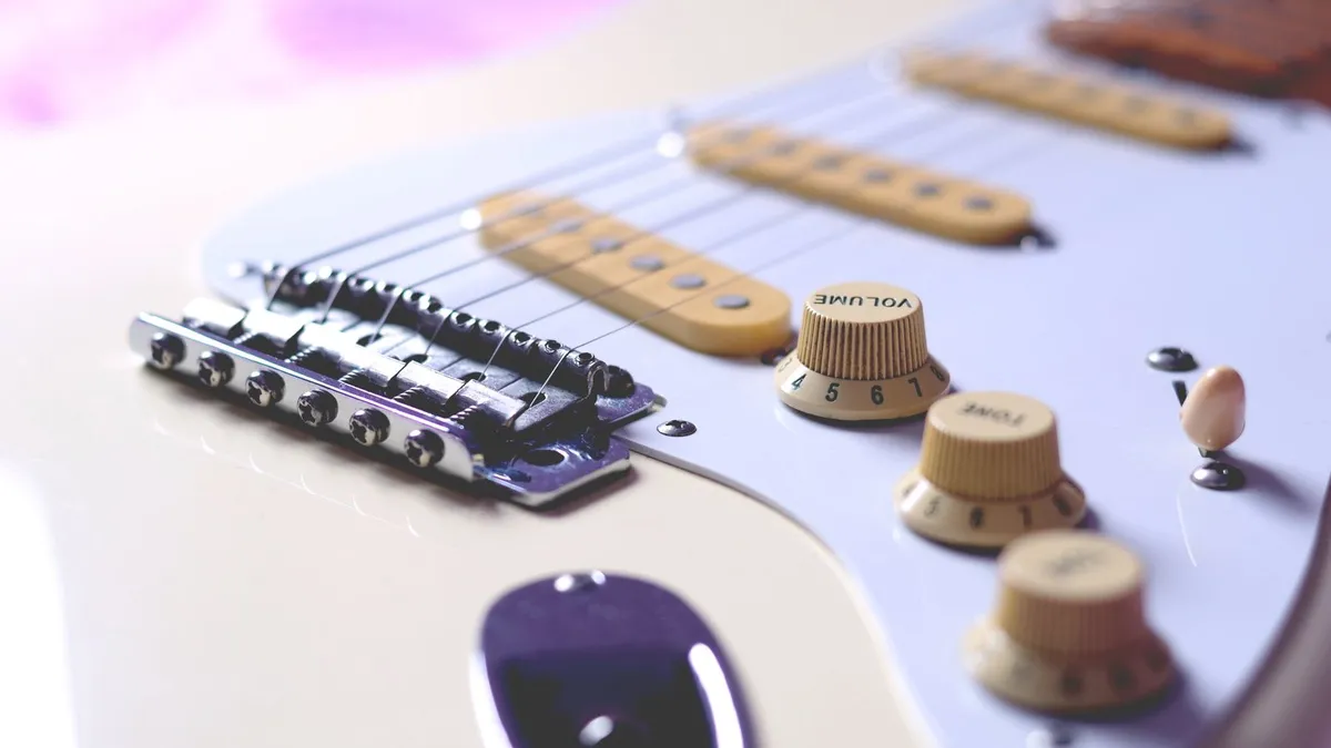 close de escudo branco com captadores single coil, botões de volume e ponte de uma Stratocaster