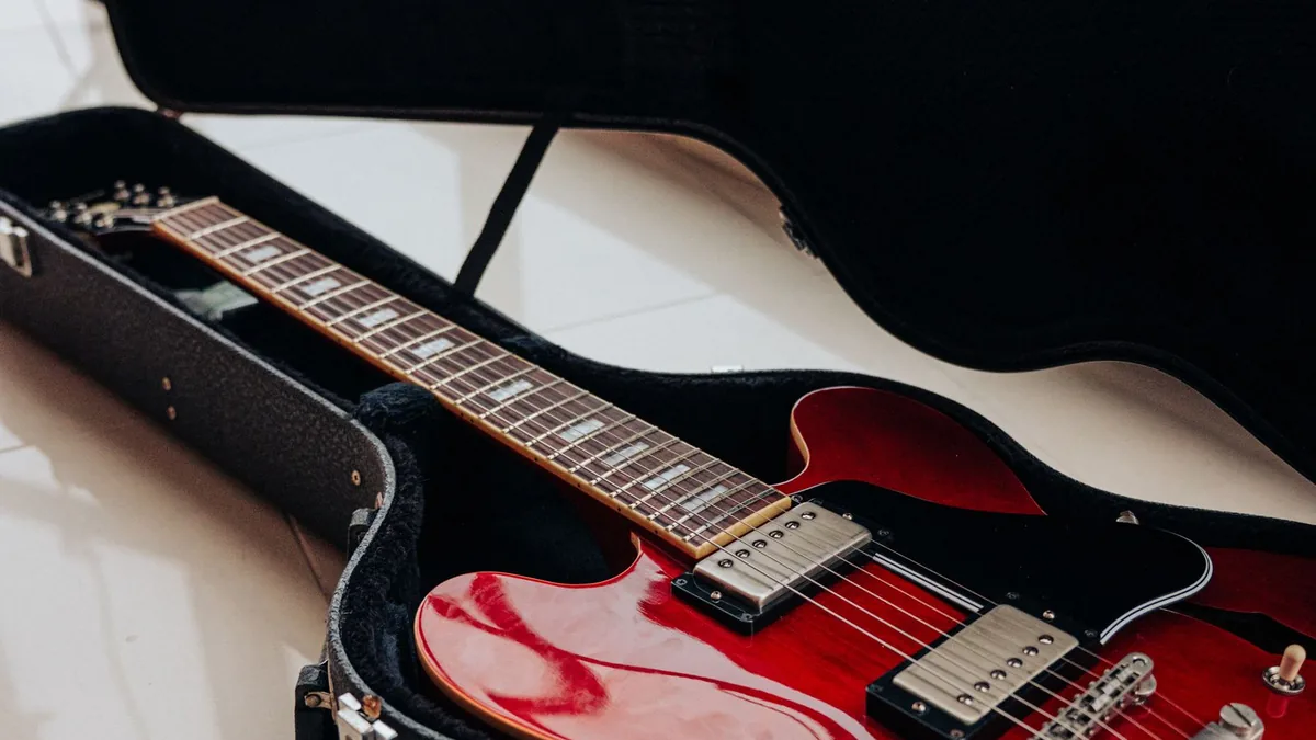 guitarra semi-acústica vermelha deitada dentro de um case rígido aberto