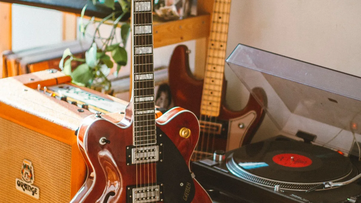 guitarra semi-acústica vinho ao lado de um amplificador Orange e uma vitrola