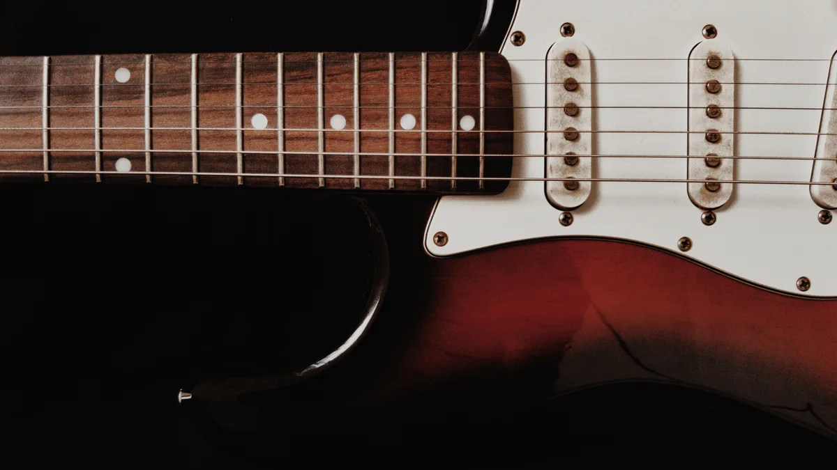 close do braço e dos captadores single coil brancos de uma guitarra estilo Stratocaster sunburst