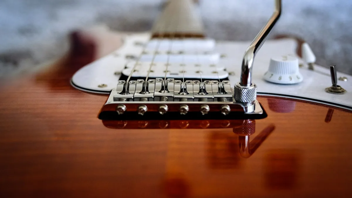 close da ponte tremolo cromada com alavanca em uma guitarra sunburst com escudo branco