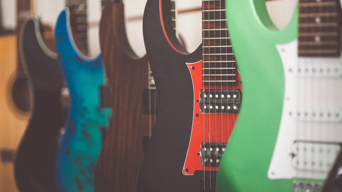 fileira de guitarras elétricas de cores e formatos diferentes expostas lado a lado