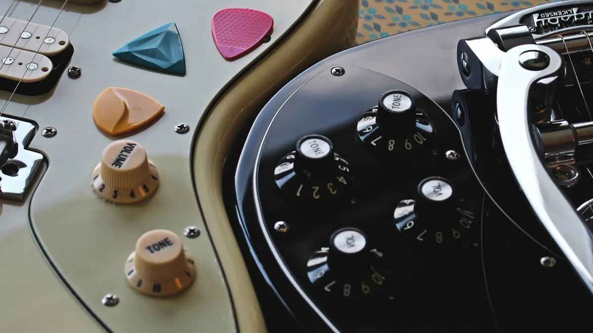 close do corpo de uma guitarra offset de cor creme com pickguard grande e botões de volume e tom
