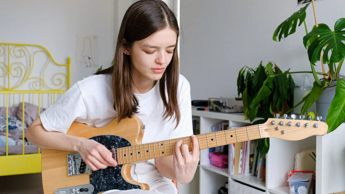 guitarrista tocando guitarra elétrica em casa, com a mão esquerda no braço