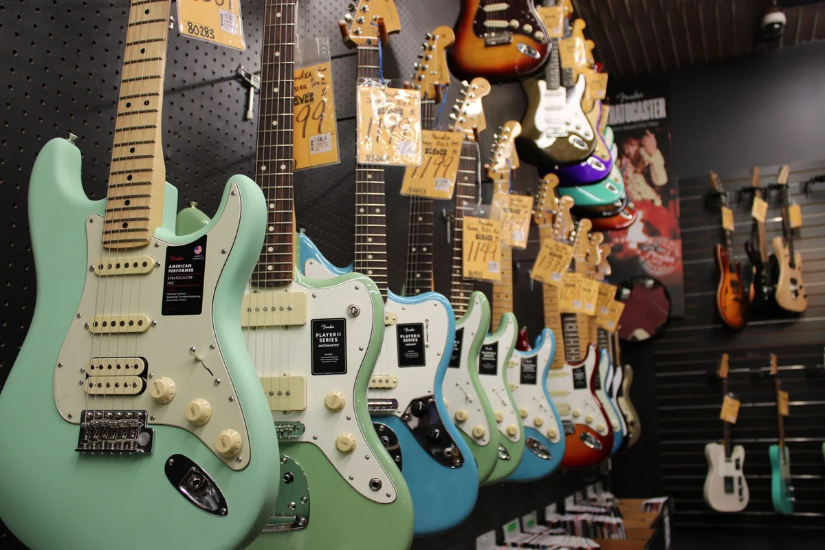 parede de loja com guitarras penduradas e etiquetas de preço presas em cada uma