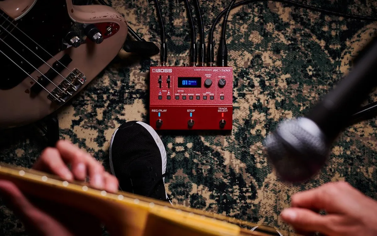 guitarrista tocando com um pedal de loop Boss RC-500 no chão do palco
