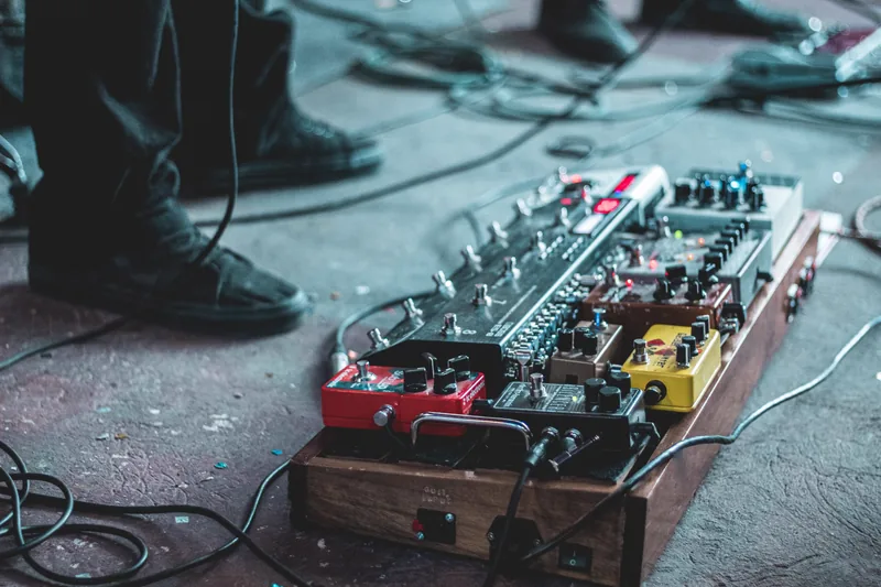 Pedaleira multiefeitos para guitarra sobre bancada de estúdio, com cabo plugado e controles visíveis