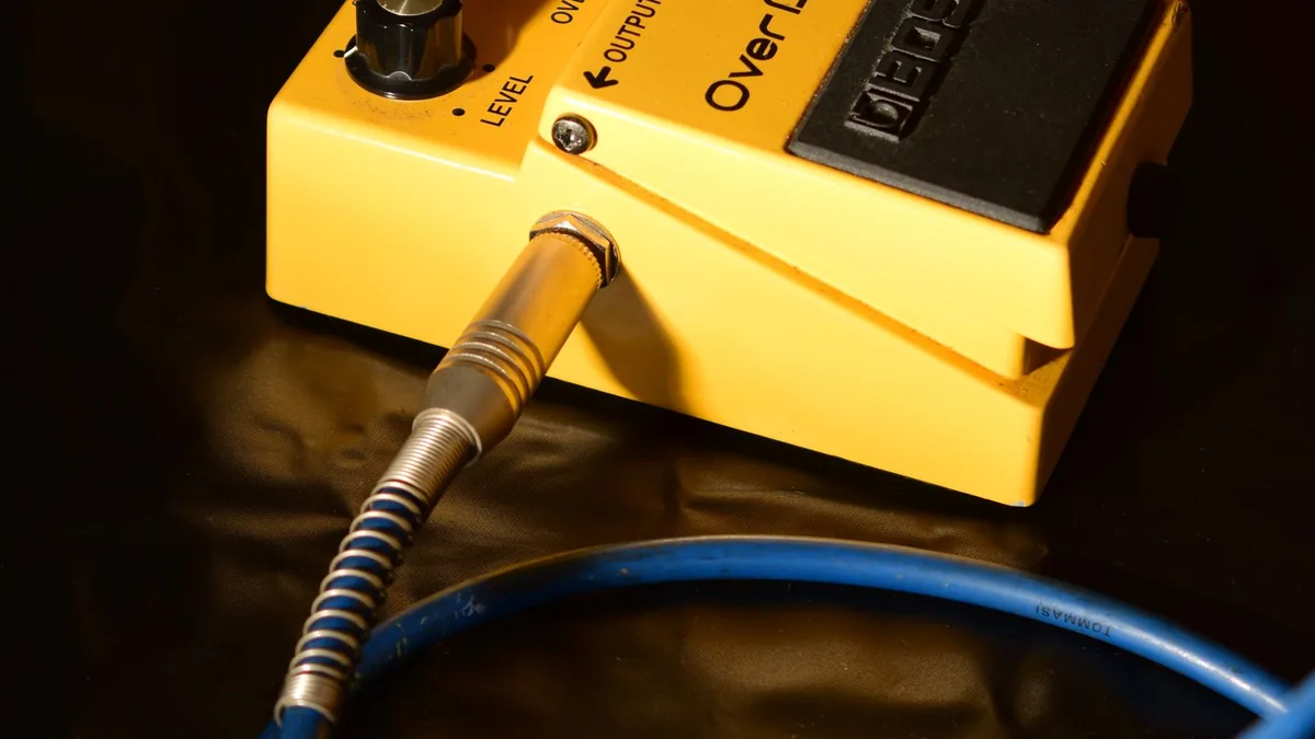 pedal de overdrive amarelo ligado a um cabo azul com malha