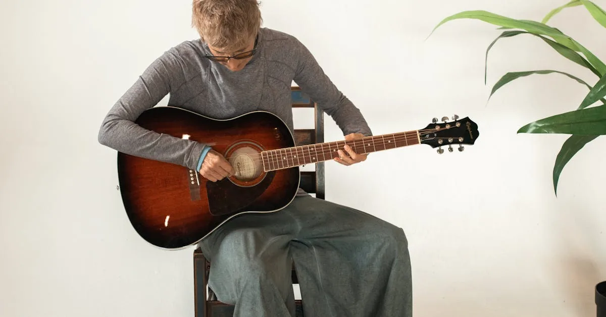 guitarrista sentado tocando um violão sunburst em um ambiente claro