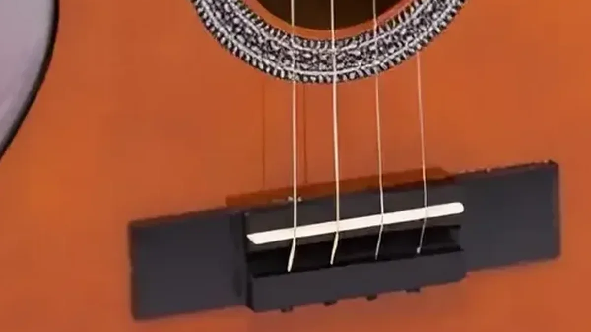 rastilho branco sobre o cavalete de um violão de nylon, com as cordas passando por cima