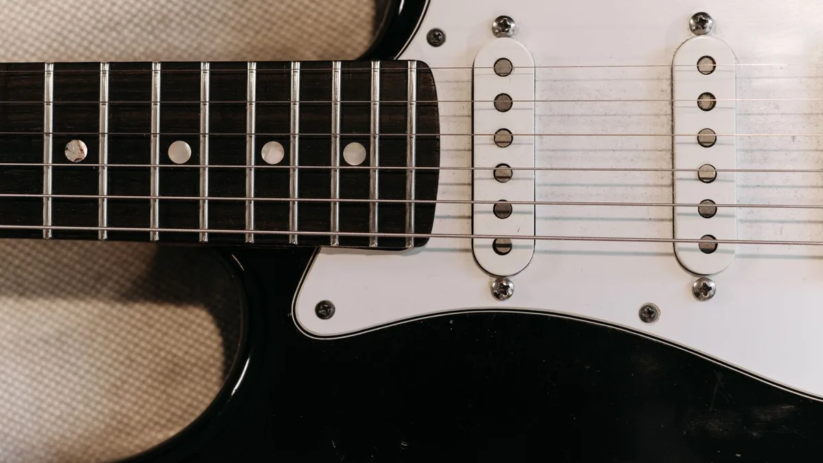 dois captadores single coil brancos no escudo de uma guitarra strato preta, vistos de cima