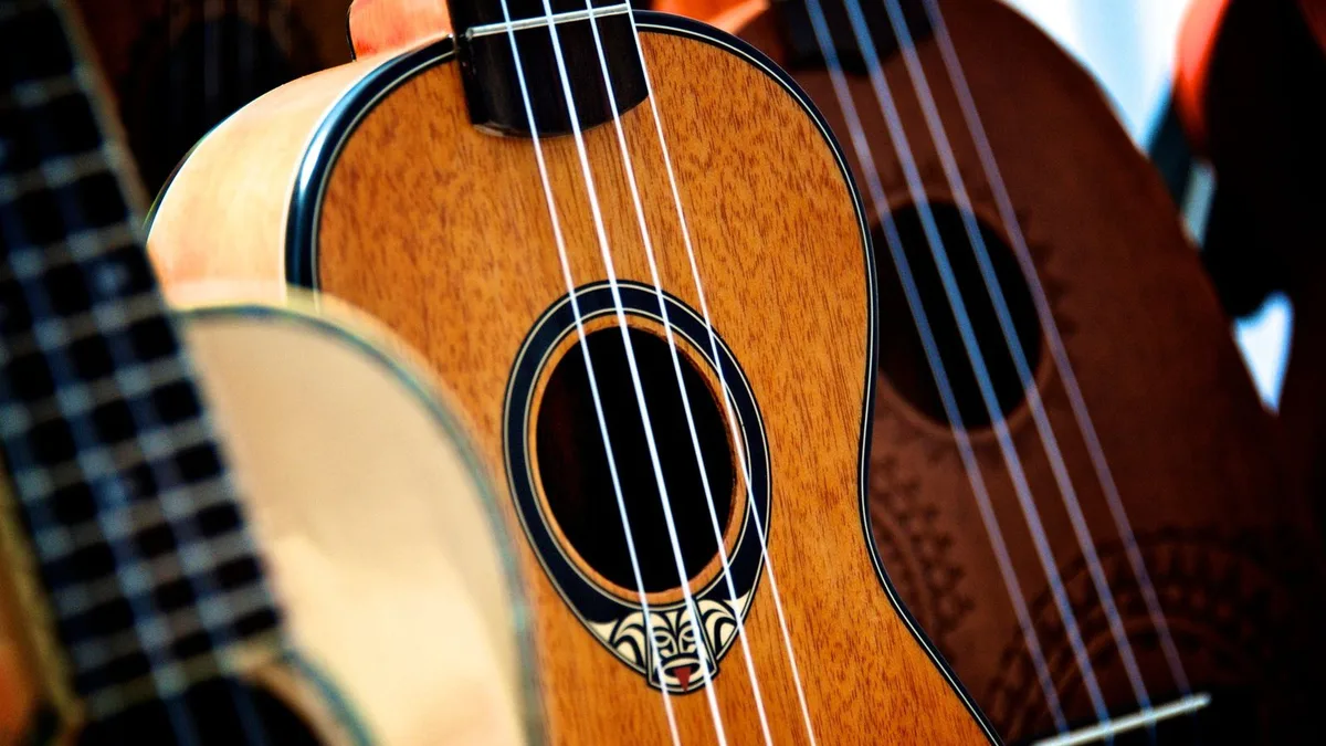 detalhe de um ukulele de madeira com as quatro cordas sobre a boca do instrumento
