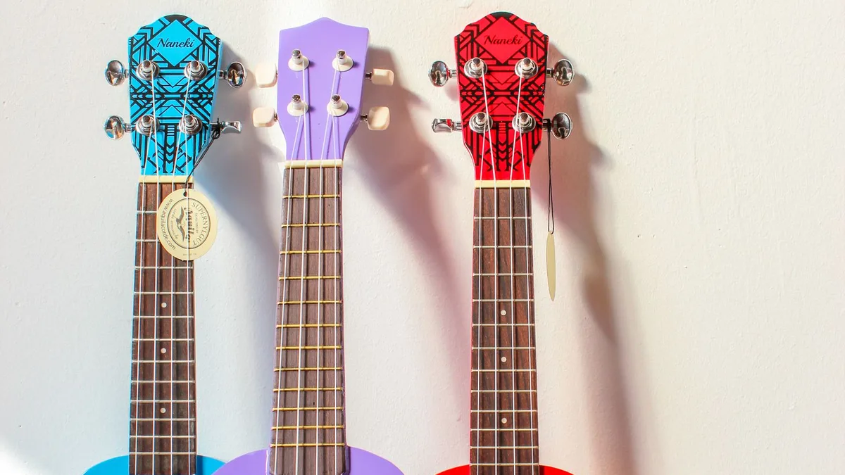 três ukuleles coloridos lado a lado mostrando o headstock e as tarraxas