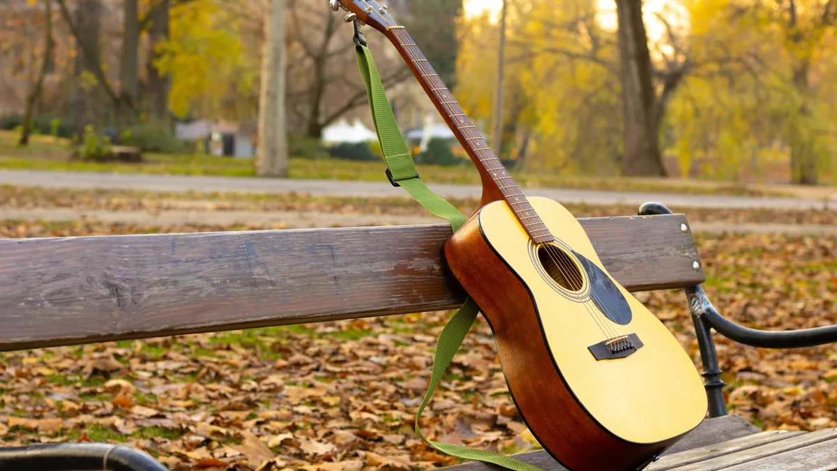 violão apoiado em banco de parque, cena ao ar livre