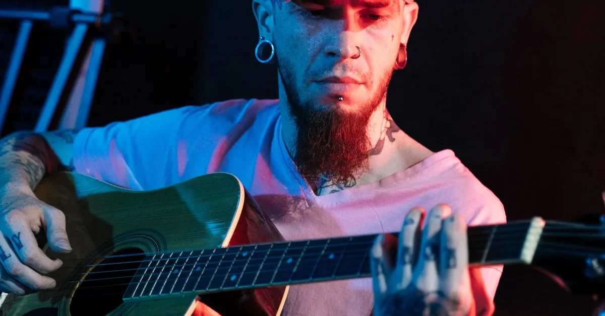 músico tocando violão de aço em ambiente com luz azul e vermelha