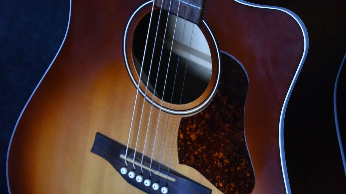 violão folk sunburst com cutaway e captação, visto de cima sobre fundo azul-escuro