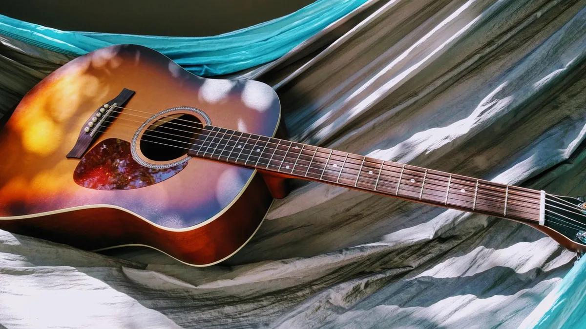 violão folk de aço com tampo sunburst apoiado em uma rede ao ar livre