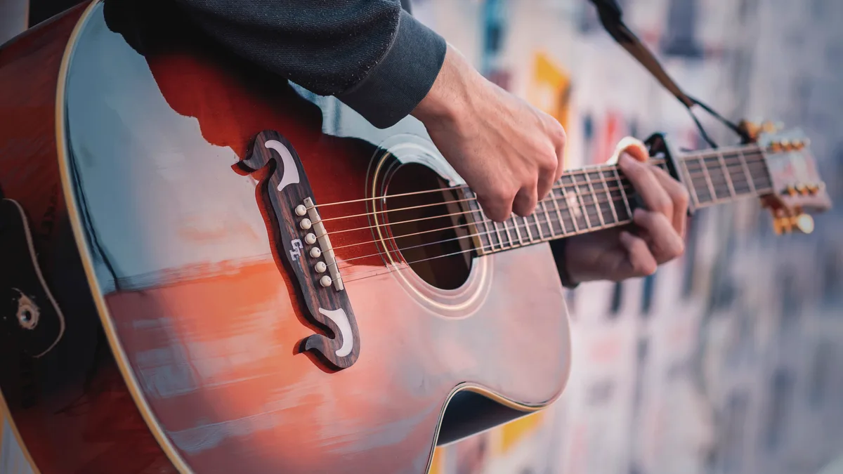 mão apoiada sobre o tampo de um violão acústico, still de estúdio