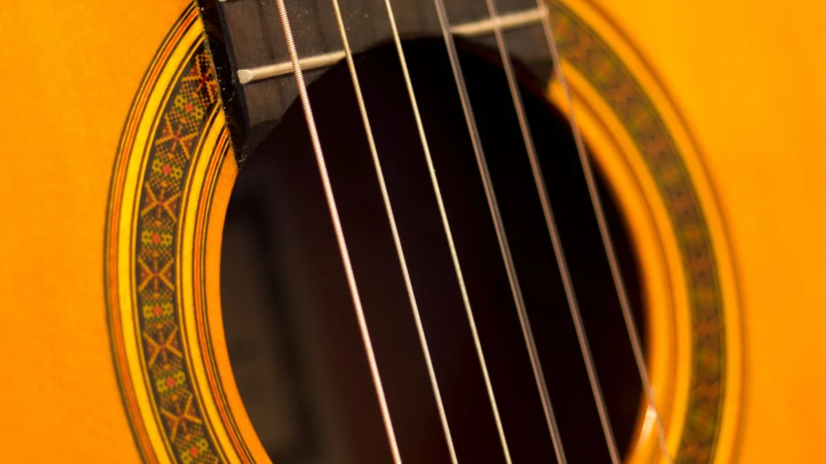 roseta decorada e cordas de um violão de tampo amarelo em close