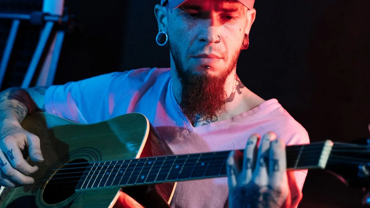 violonista de barba tocando um violão eletroacústico sob luz vermelha e azul de palco